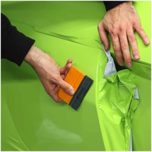 La spatola Alcantara Steinel in uso per applicare la pellicola su una superficie verde. Set da 2 pezzi.