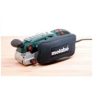 Ponceuse à bande Metabo BAE 75 vert-gris avec sac à poussière sur surface en bois.