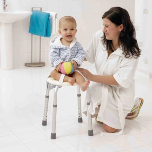 Enfant assis sur tabouret de douche Ridder blanc réglable en hauteur dans salle de bain.