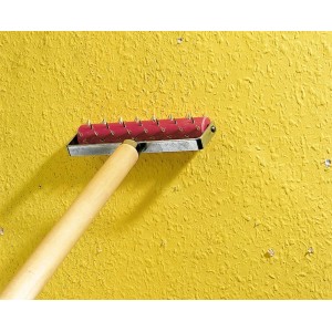 Rullo chiodato per carta da parati LUX 15 cm con manico in legno per forare la carta da parati su parete gialla.