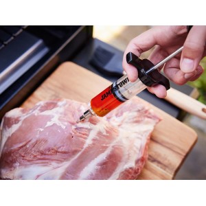 Seringue à marinade Jamestown injectant de la marinade dans de la viande sur une planche à découper en bois.