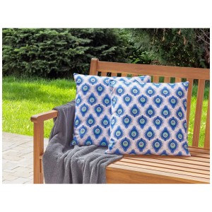 Zwei Beliani Gartenkissen Ceriana mit blauem Pfauenfedermuster auf Holzbank im Garten. Polyester, 45x45 cm, 2er-Set.