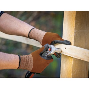 Mani con guanti LUX Multi (taglia 7) che avvitano nel legno. Guanti da lavoro per il fai da te.