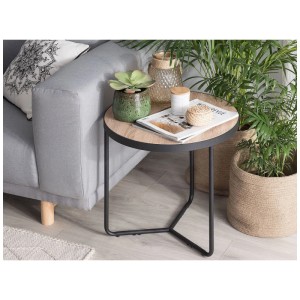 Tavolino rotondo Melody con piano in MDF chiaro e struttura in metallo nero, stile industriale, accanto al divano.