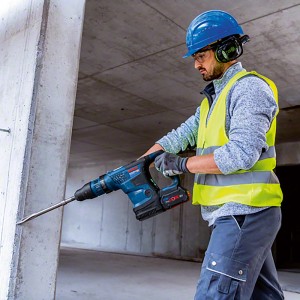 Trapano a percussione a batteria Bosch Professional GBH 18V-36 C in uso durante la foratura nel cemento.