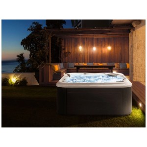 Jacuzzi extérieur Beliani Tularosa avec éclairage LED bleu dans un jardin la nuit. Ambiance relaxante.