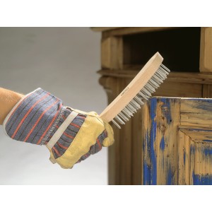 Main gantée utilisant une brosse métallique LUX (4 rangs) pour enlever la rouille du bois.