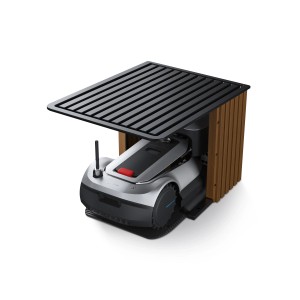 Robot tondeuse Ecovacs GOAT G1-2000 dans son garage. Le robot de tonte est garé sous un abri au toit à lamelles.