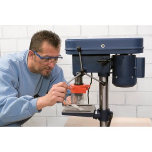 Homme portant des lunettes de protection bleues LUX Panorama perçant avec une perceuse à colonne.