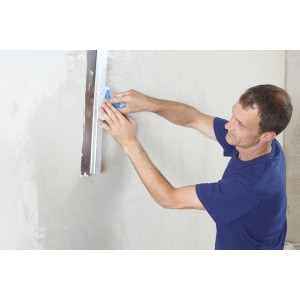 Uomo che liscia il muro con stucco Knauf Multifinish e strumento. Accessori per cartongesso.