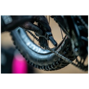 Brosse de nettoyage Muc-Off Claw Brush utilisée sur une chaîne et un pignon de vélo.
