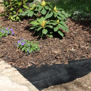Telo pacciamante nero Windhager 50 g/m² in aiuola sotto pacciame di corteccia.