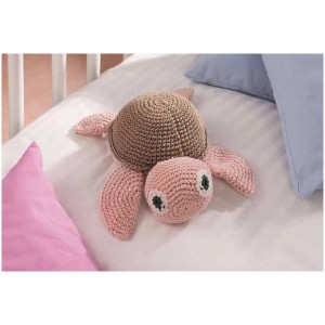 Tartaruga rosa all'uncinetto in cotone (Wolle Cotton) su un letto.