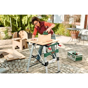 Donna che leviga il legno su un banco da lavoro Bosch PWB 600 in giardino.